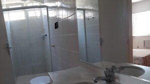 A bathroom with a toilet, a sink, and a shower area.