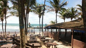 A beachside restaurant with outdoor seating and a view of the ocean.