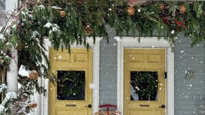 Un edificio con dos puertas amarillas, un porche de madera y un adorno navideño.