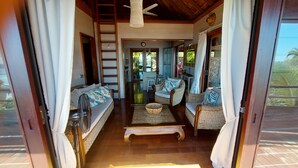 A cozy living area with wicker furniture, a wooden coffee table, and a view of the outdoors. - Stunning ocean & lagoon view in a completely renovated, entirely equipped villa (Haapiti)