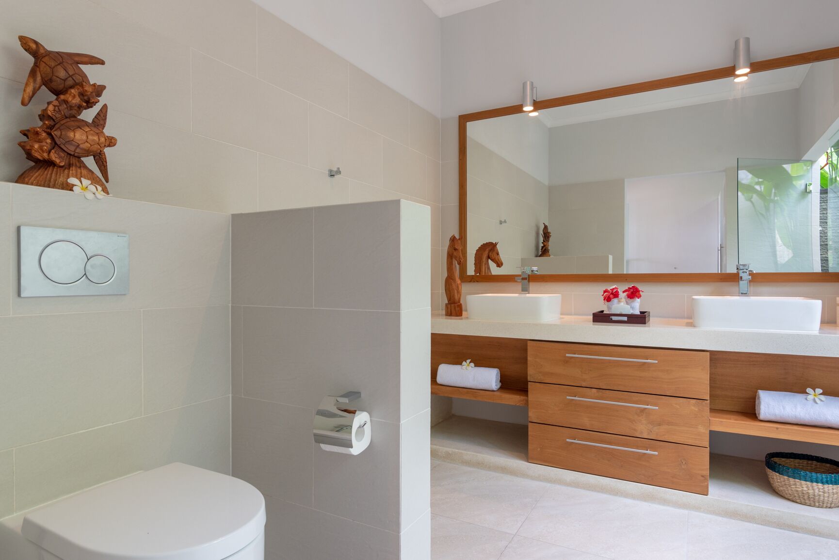 A modern bathroom with a toilet, a shower, and a vanity with two sinks and a large mirror.