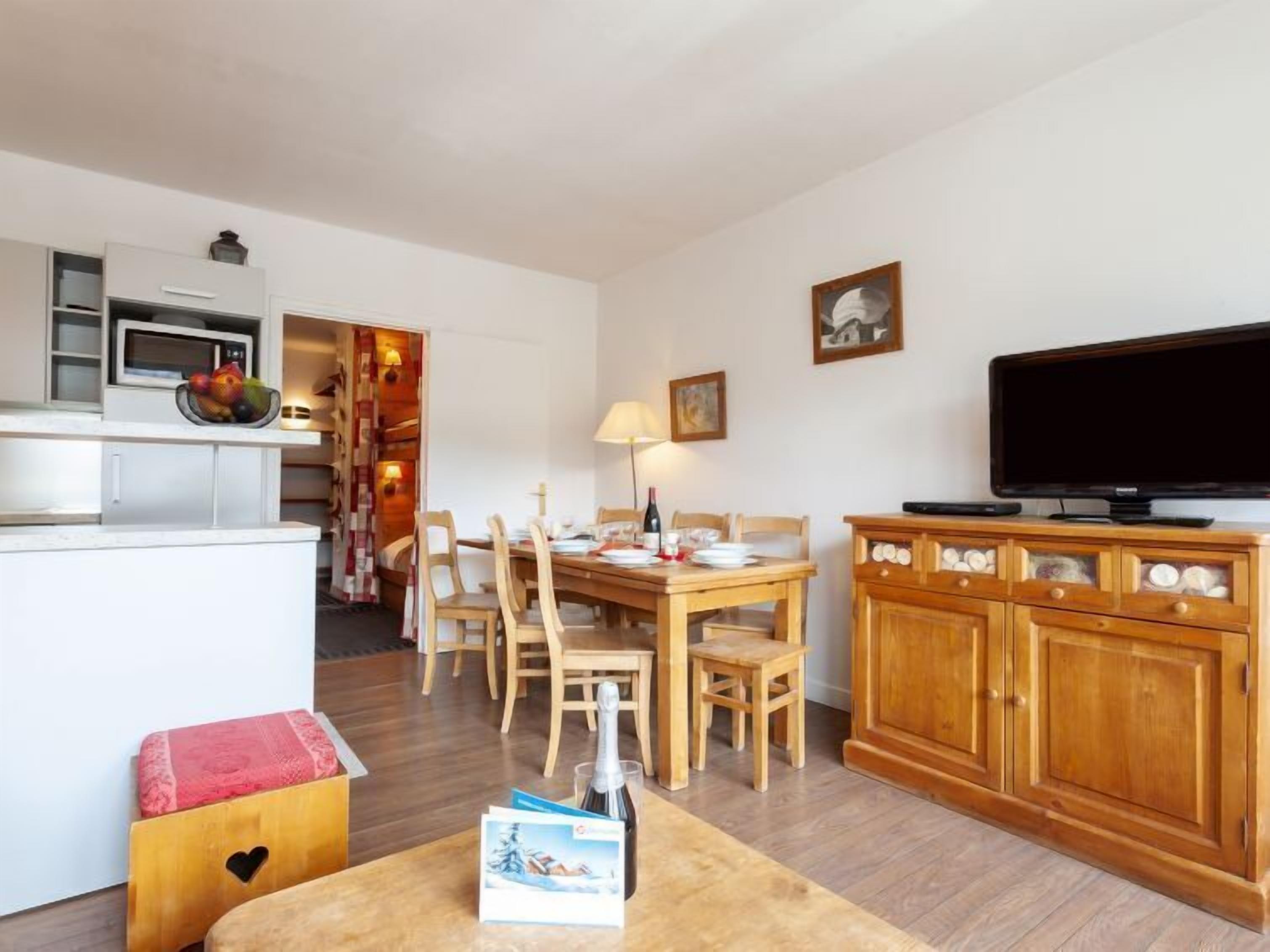 A compact living space with a kitchenette, dining area, and a television.