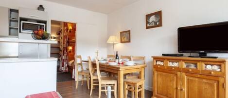A compact living space with a kitchenette, dining area, and a television.