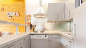 A modern kitchen with white cabinetry, a built-in stove, and a wooden wall. - Le Bec Rouge (Le Lac) by Interhome (Tignes)