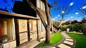 Una casa moderna con una terrazza in legno, un vialetto in pietra e un prato curato.