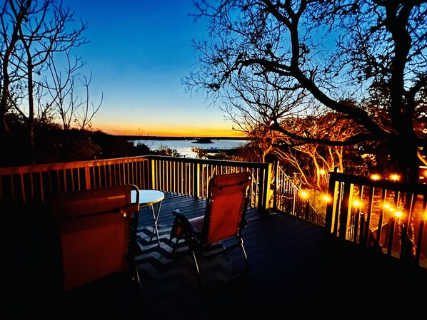 A deck with chairs and a table, overlooking a body of water and a sunset. - Little Big Sunset In Private Oasis (Volente)