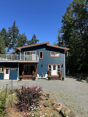 Un bâtiment à deux étages, à la façade bleue, doté d’un balcon et d’une allée gravillonnée.