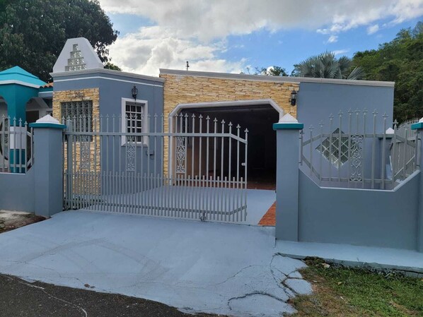 Stunning entrance to a beautifully landscaped property with a modern gate and pillars.