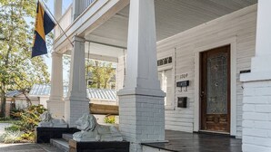 Un bâtiment blanc avec un porche, une porte en bois et une boîte aux lettres.