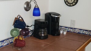 A kitchen with a wooden counter, a coffee maker, a kettle, a clock, and a blue lamp. - Studio Close to Everything (Belgrade)