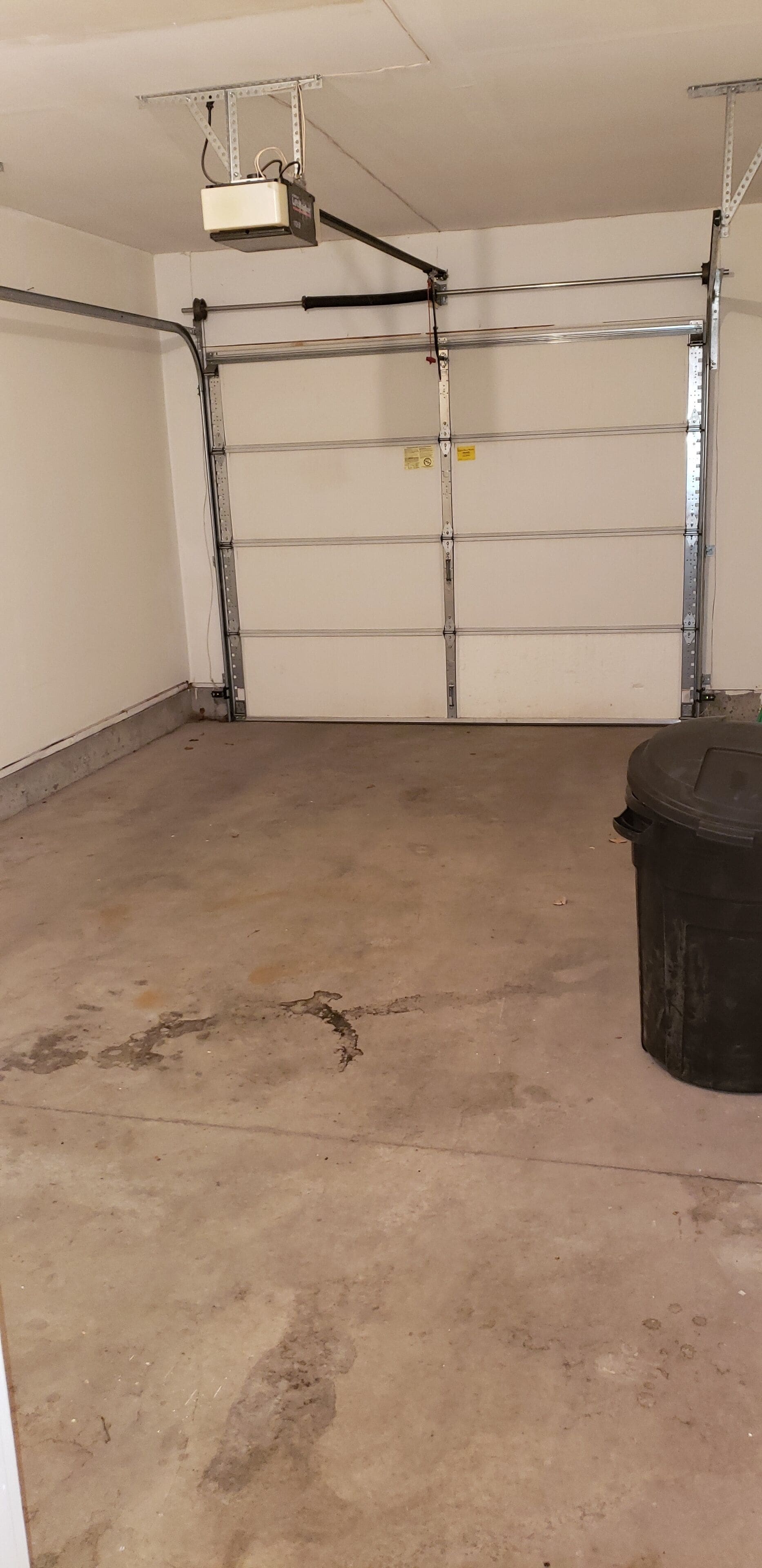A garage with a concrete floor, metal shelving, and a projector mounted on the ceiling.