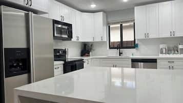 Una cocina moderna con armarios blancos, electrodomésticos de acero inoxidable y una isla grande.