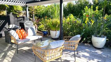 Un patio al aire libre con mobiliario de mimbre, una parrilla y plantas en macetas.
