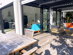 Un área de patio exterior con una mesa y sillas de madera, un sofá azul y una silla de mimbre.