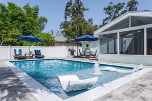 Een zwembad met ligbedden en parasols, een jacuzzi en een overdekte zithoek.