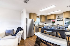 A modern kitchen with a refrigerator, stove, and dining area with a table set for two.