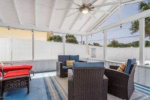 A covered patio area with wicker furniture and a ceiling fan.