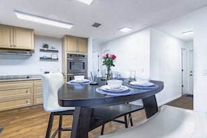 A modern kitchen with a dark dining table, white chairs, and a vase of flowers. - Stunning Pool Home, Near Siesta Key & Dog Friendly (Sarasota)