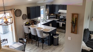 Una cocina moderna con armarios oscuros, una isla central y un comedor con sillas y mesa.