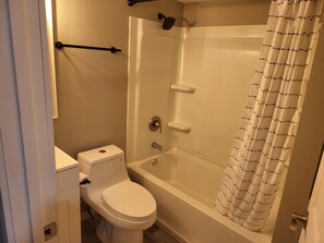 Un baño con inodoro, bañera y cortina de ducha.