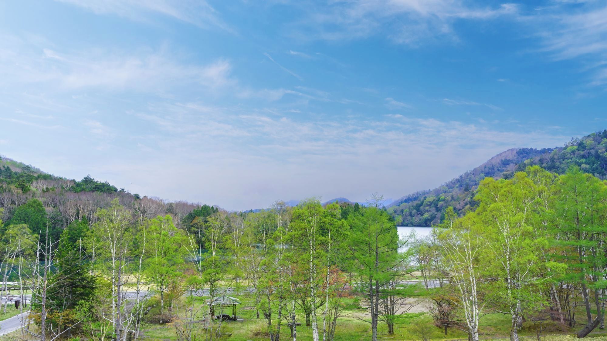 A mountainous landscape with a clear sky, a lake, and a gazebo in the foreground.