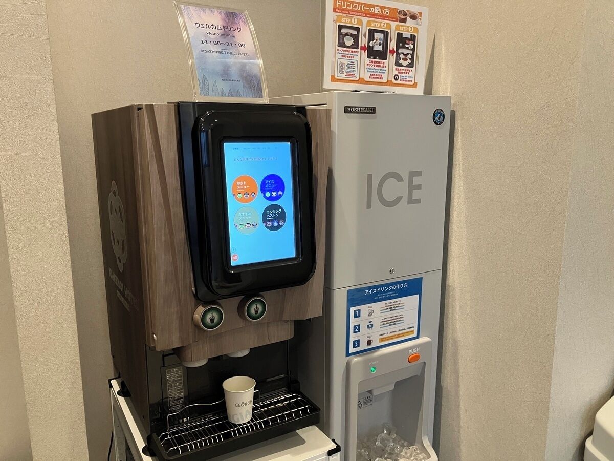 Uma máquina de bebidas automática com tela digital, porta-copos e dispensador de bebidas.