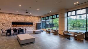 A spacious lounge area with a stone wall, large windows, and modern furniture.