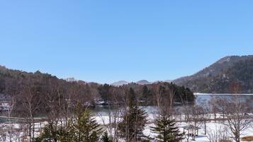 A winter landscape with a lake, snow-covered ground, and trees.