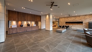 A spacious lobby with a reception desk, seating area, and a stone wall.
