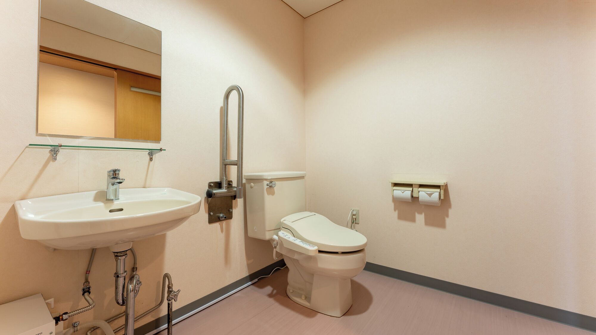A bathroom with a sink, toilet, and a glass shelf above the mirror.