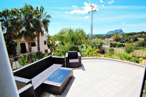 Una terraza en la azotea con mobiliario exterior, vista del paisaje circundante y una línea eléctrica a lo lejos.