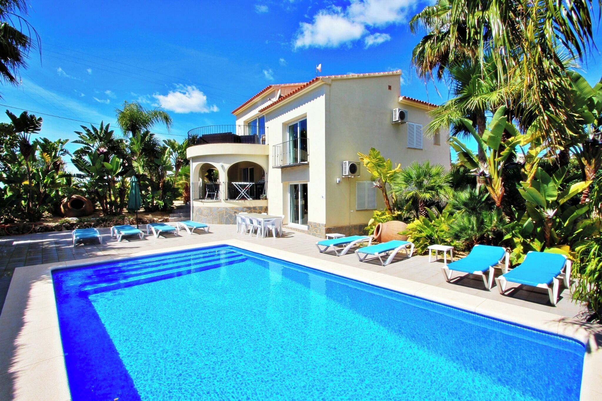 A swimming pool with lounge chairs and a building with a balcony.