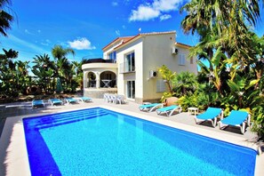 A swimming pool with lounge chairs and a building with a balcony.