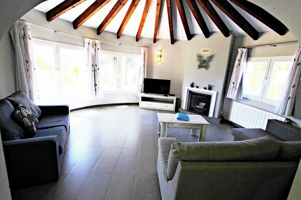 Una sala de estar con chimenea, televisor y sofá.