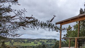 Un jardin agrémenté de fleurs violettes, une pergola en bois et une vue sur des collines ondoyantes.