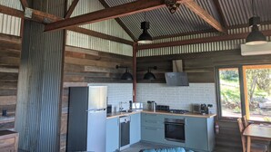 Une cuisine rustique avec un mur recouvert de briques, des appareils en acier inoxydable et une table à manger en bois.