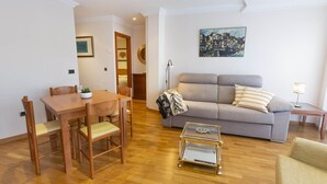 Una sala de estar con una mesa de comedor de madera, sillas, un sofá y una mesa de centro de vidrio.