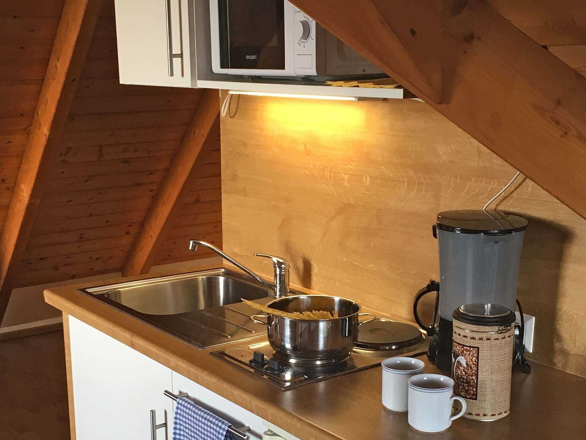 A compact kitchen with a sink, stove, and microwave.