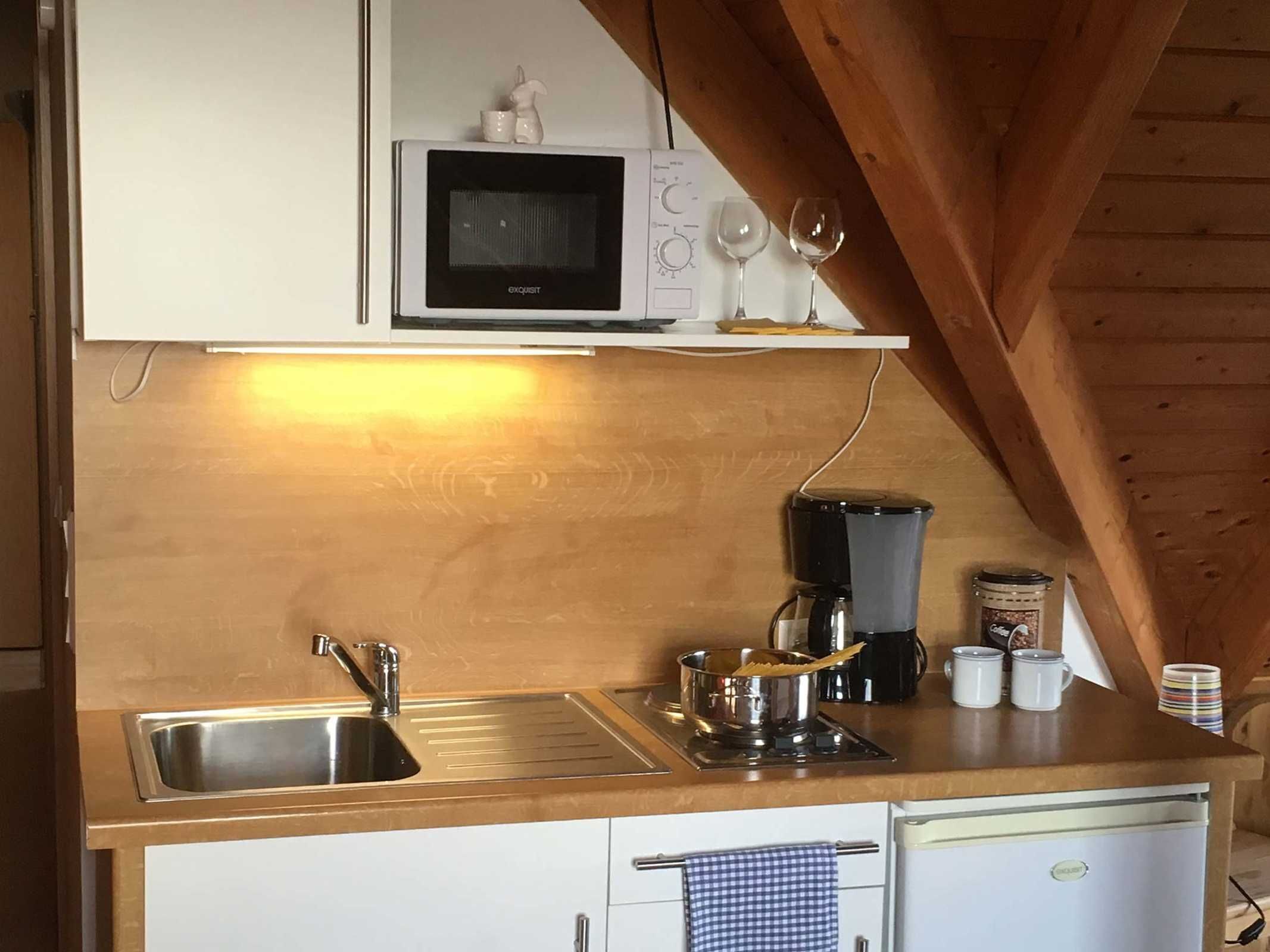 A kitchen with a microwave, coffee maker, and a sink.