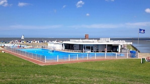Un espace piscine avec un bâtiment sur lequel est apposée une enseigne indiquant « Schwimmbad ».