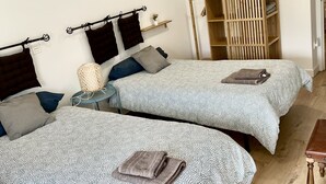 Une chambre avec deux lits, une armoire en bois, un miroir et une petite table.