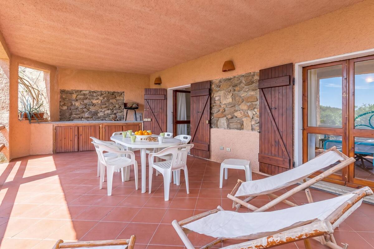A patio with a table and chairs, a stone wall, and a view of the landscape.