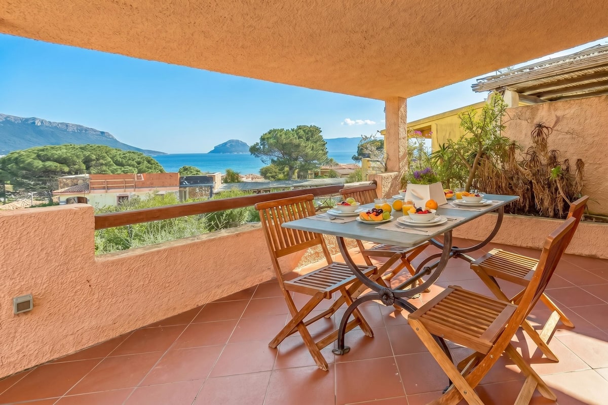 A terrace with a table set for breakfast, overlooking a coastal view.