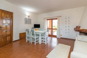 Un coin repas avec une table et des chaises, un téléviseur et une porte en bois.