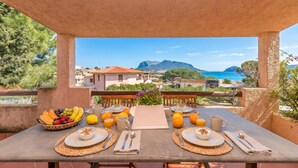 A table set for breakfast with a view of the sea and mountains. - Appartamenti Erica (Golfo Aranci)