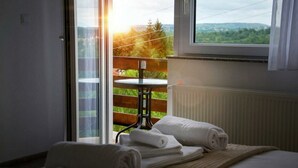 A hotel room with a bed, a window with a view of greenery, and a table with towels. - Apartment Josipa (Rakovica)