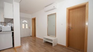 A clean, modern kitchen with white cabinets and a microwave. There is a wooden bench and a large mirror on the wall. - Apartment Josipa (Rakovica)