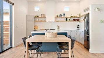 A modern kitchen with a central island, black chairs, and a built-in refrigerator.