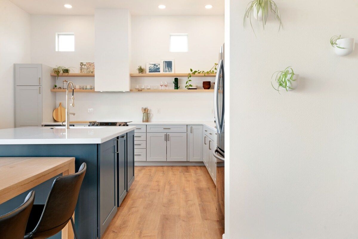 A modern kitchen with a central island, built-in appliances, and a dining area with a wooden table and chairs.