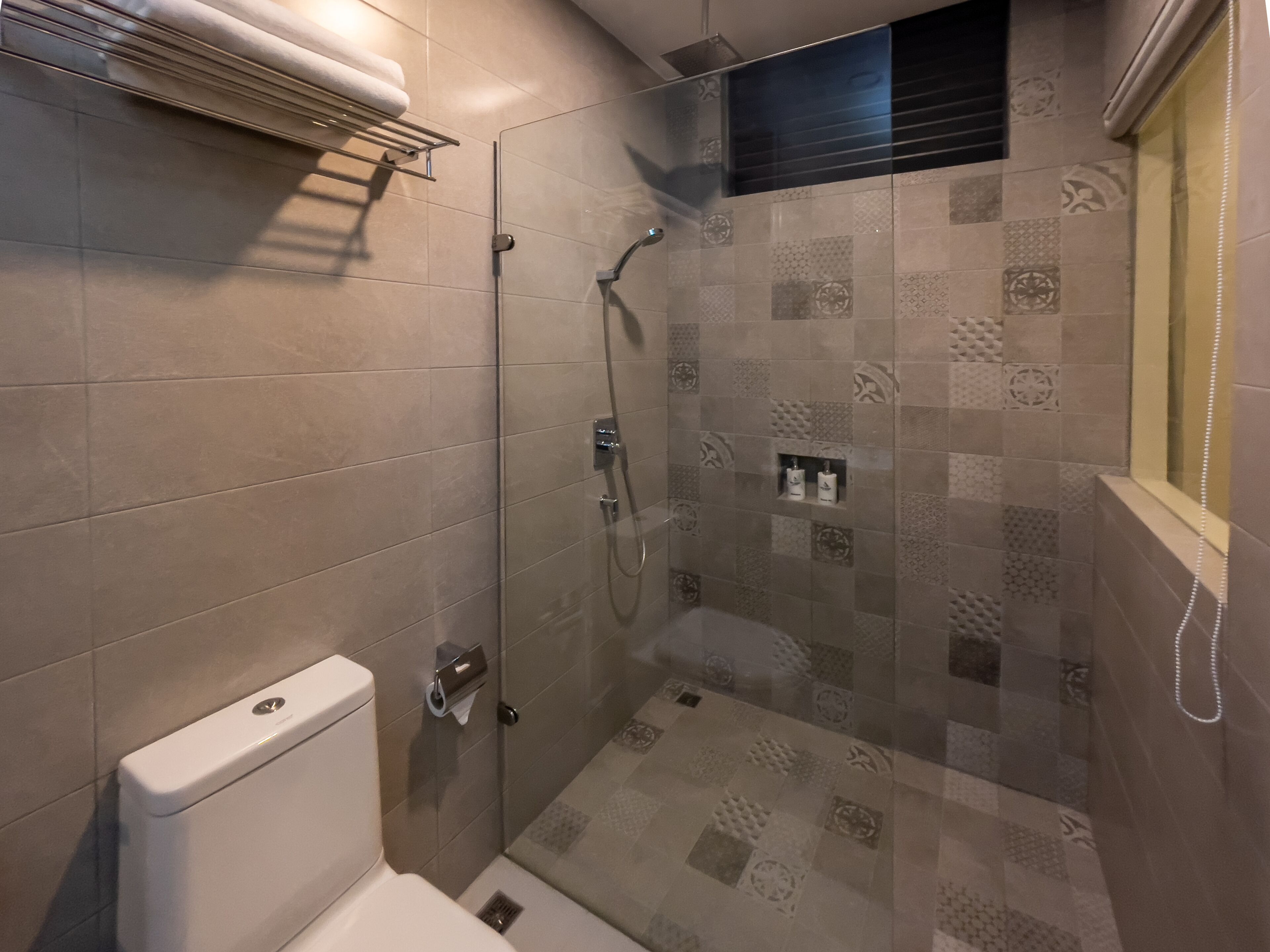 A modern bathroom with a toilet, a shower with a glass door, and a tiled floor.